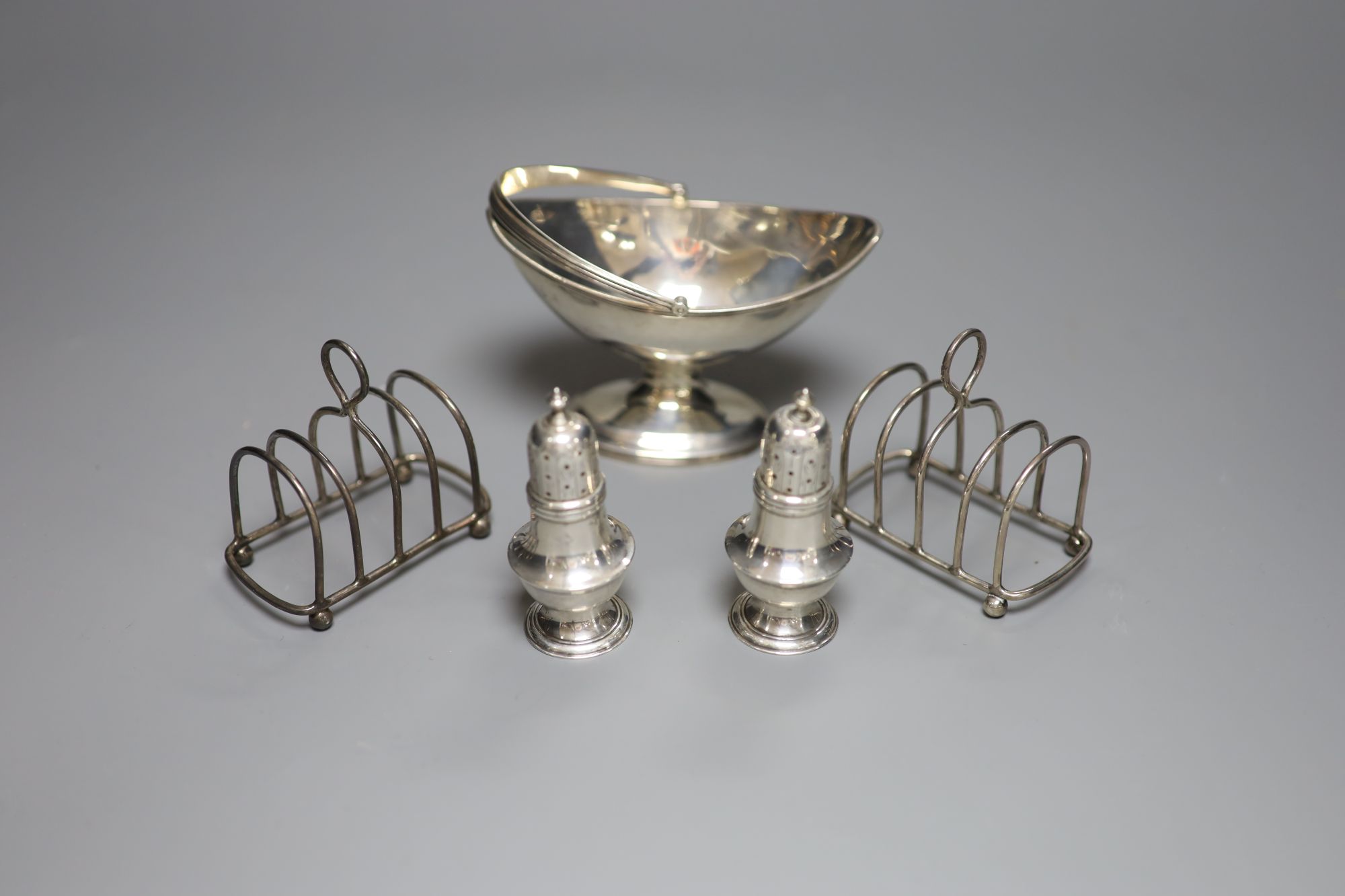 A small George III silver basket, London, 1785, a pair of Victorian silver peppers and a pair of later silver toastracks, 6.5oz.